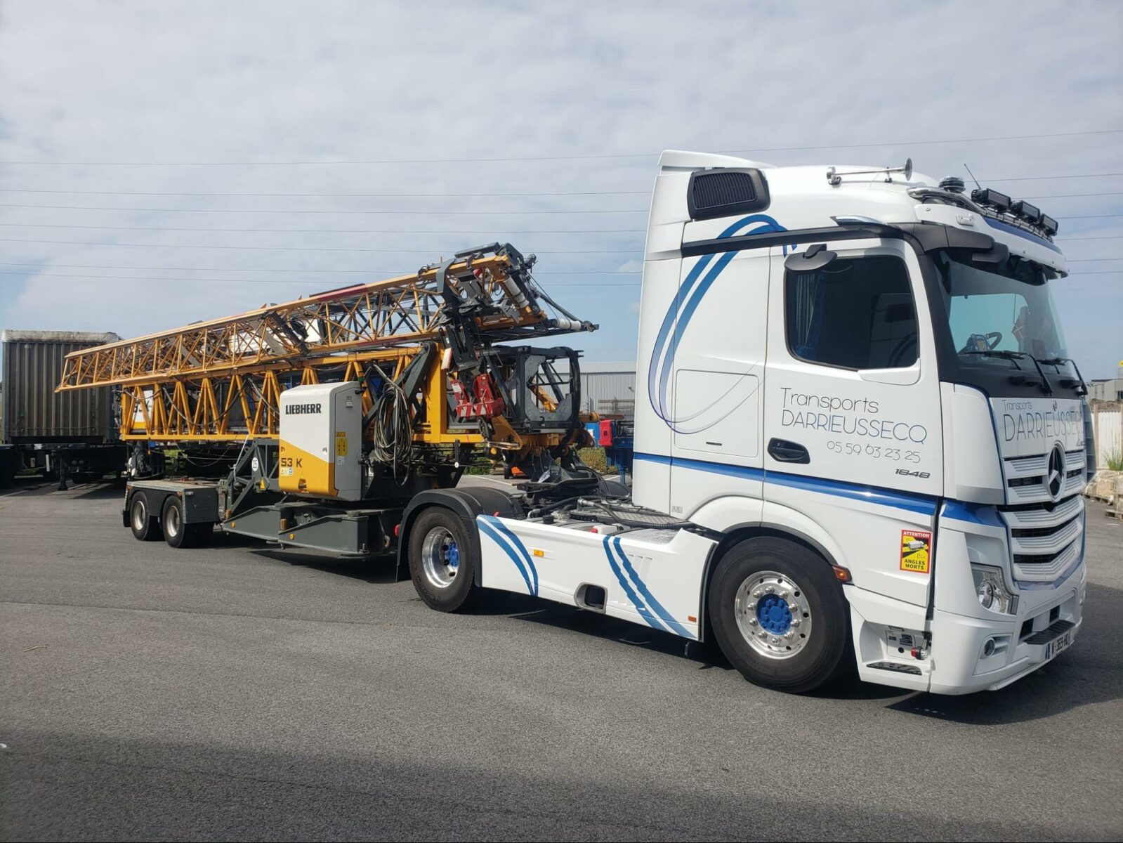 Une grue de chantier en train d’être transporté sur un camion plateau